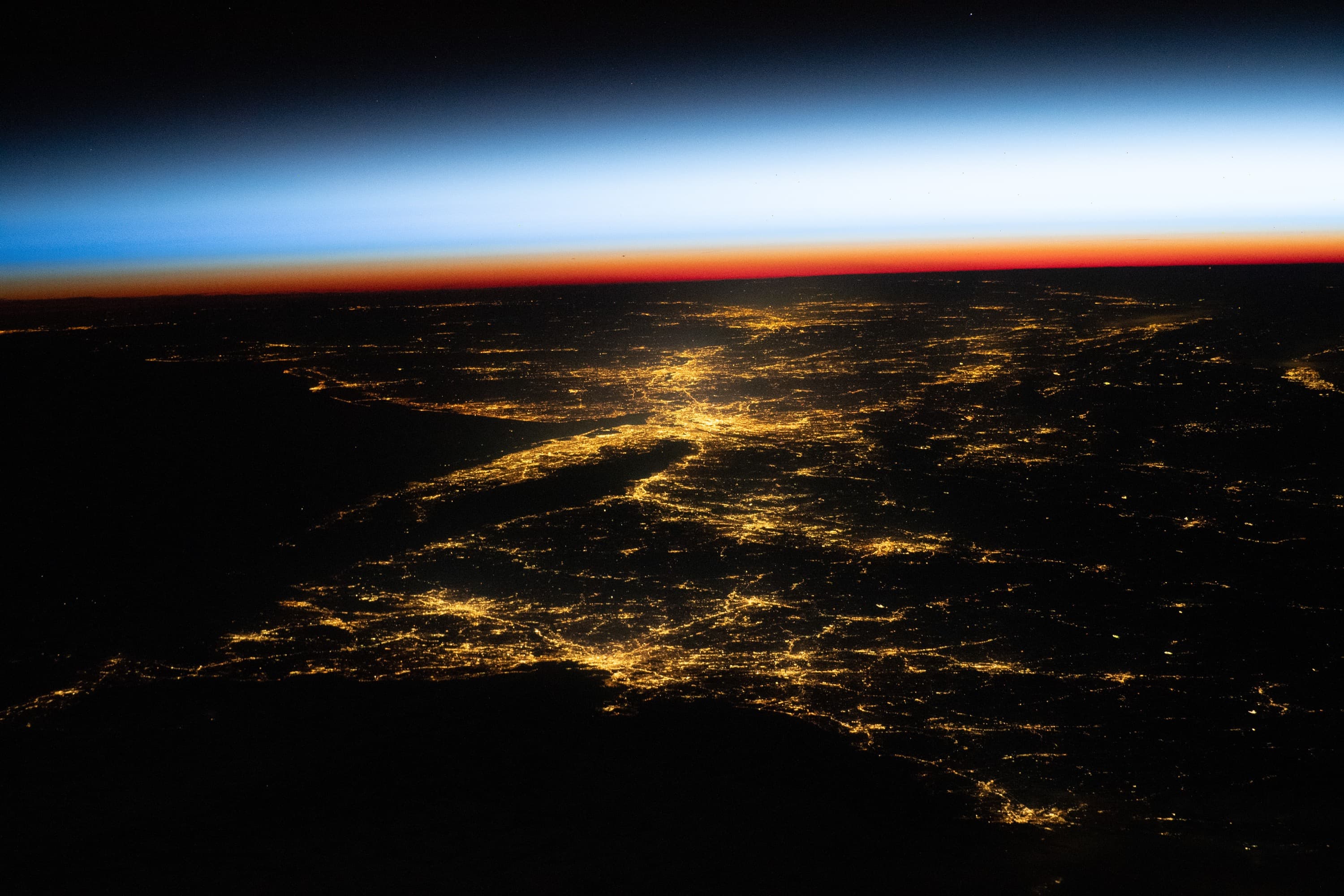The United States at night, seen from the International Space Station, with city lights glowing along the horizon